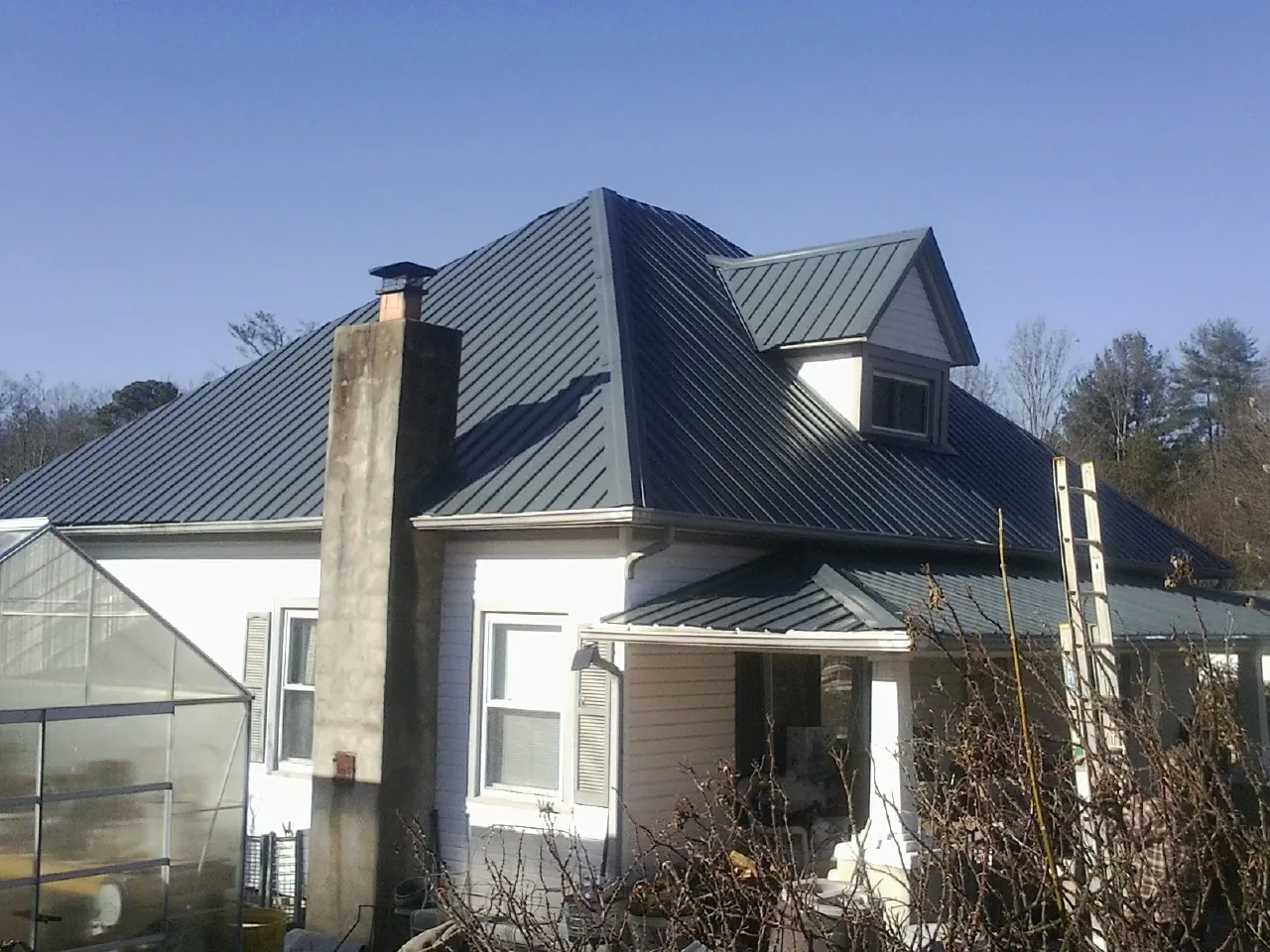 Dark blue standing seam metal roof on a white farmhouse with dormer — Slate & Tile Roof Repair by Roofing Brothers in Ashwood