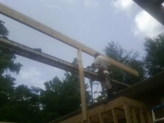 Carpenter setting a ridge beam over a new addition frame — Ice Dam Removal by Roofing Brothers in Ashwood