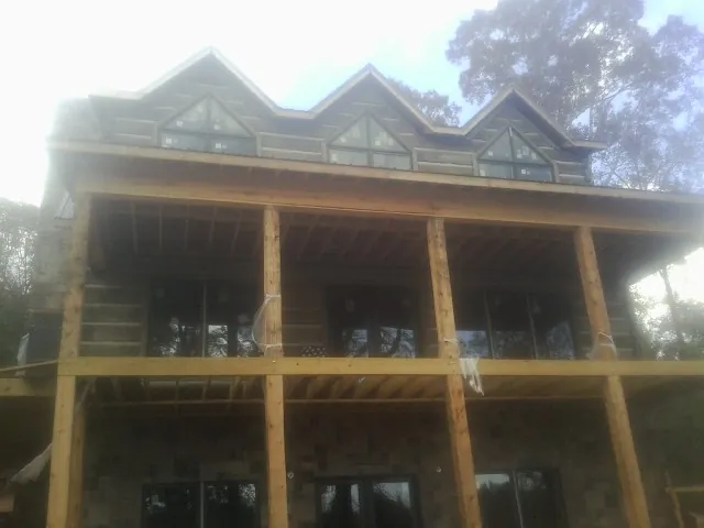 Dormers and porch framing on a large log home under construction — Roof Coating work by our crew in Ashwood