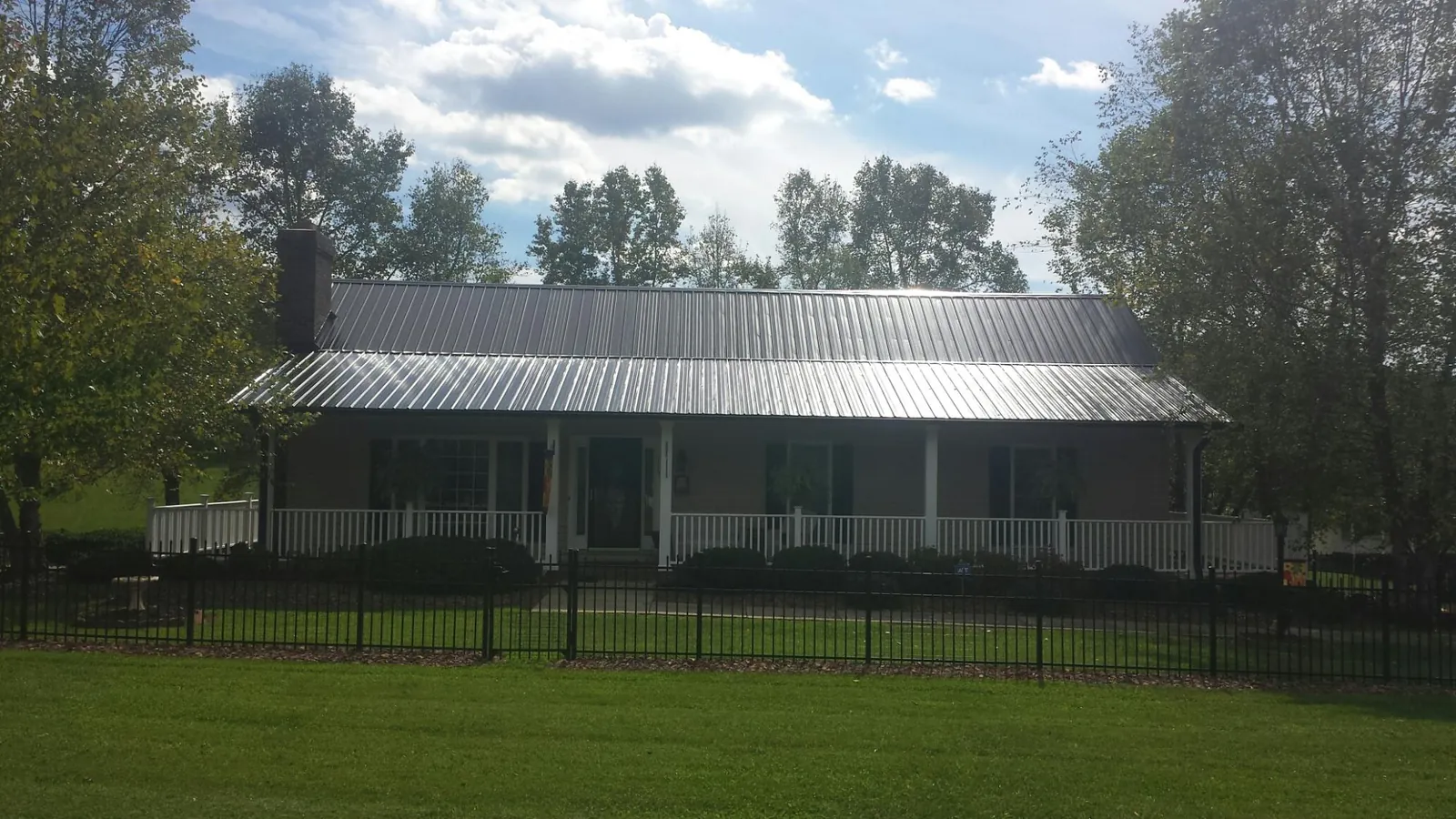 Gray metal roof on a brick ranch with a full width front porch — Gutter Guard Installation work by our crew in Ashwood