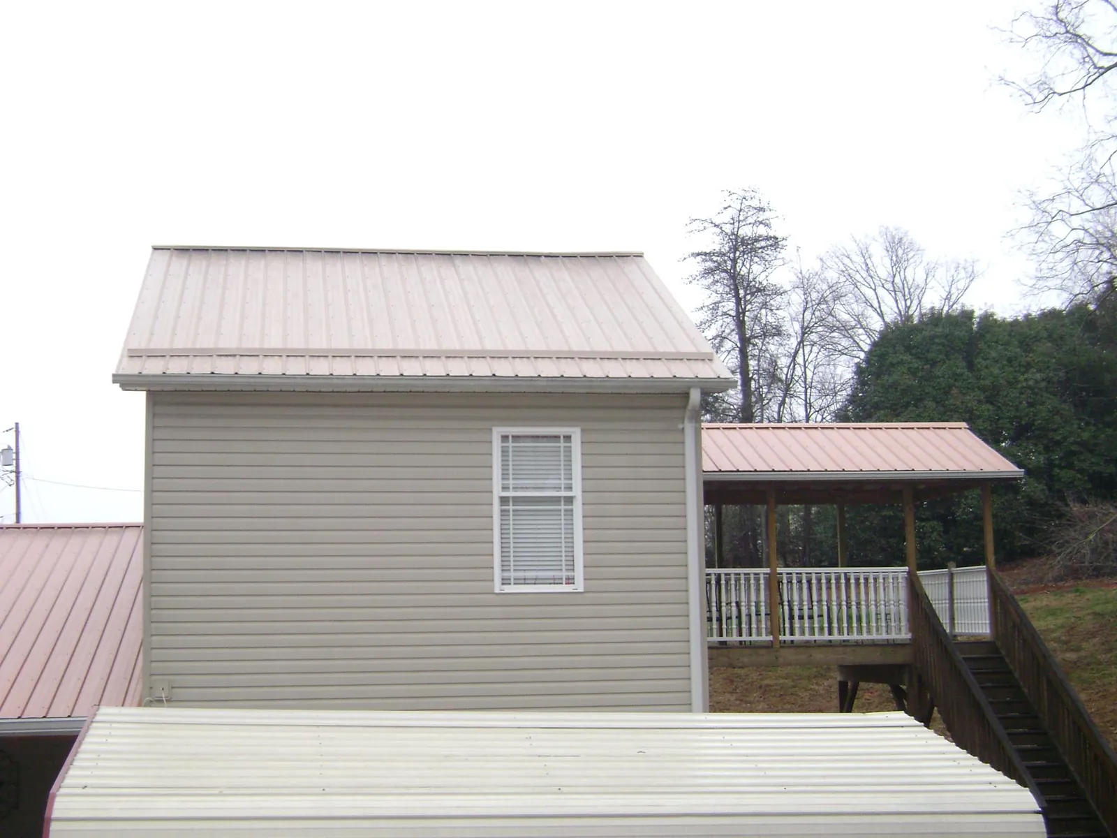 Tan metal roofs on a two story addition and attached porch, from a Roof Replacement job in Ashwood