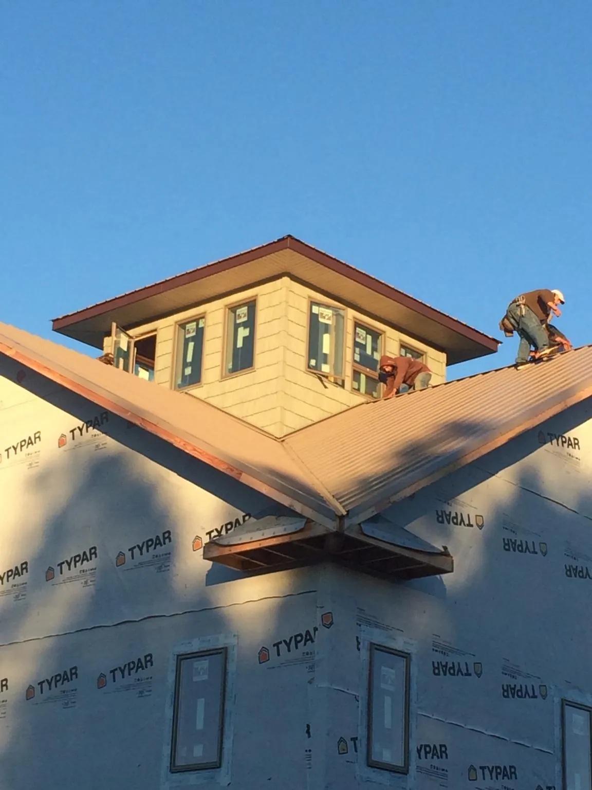 Roofers working around a rooftop cupola on a new metal roof at sunset — Roof Waterproofing in Ashwood by Roofing Brothers